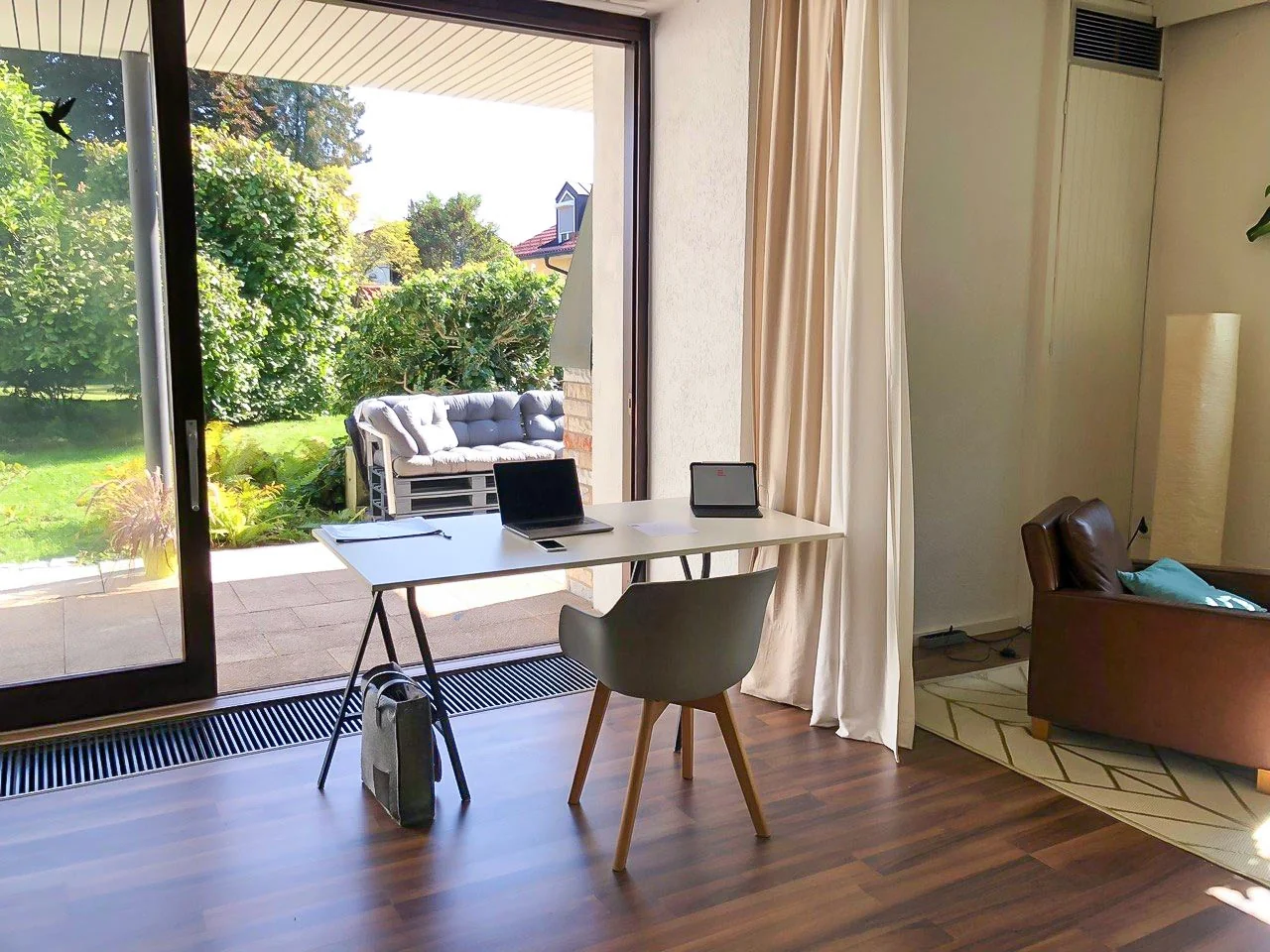 Innenansicht Veranstaltungsraum Herzstudio Neufarn mit Arbeitsplatz an der Terrassentür und Blick in den Garten